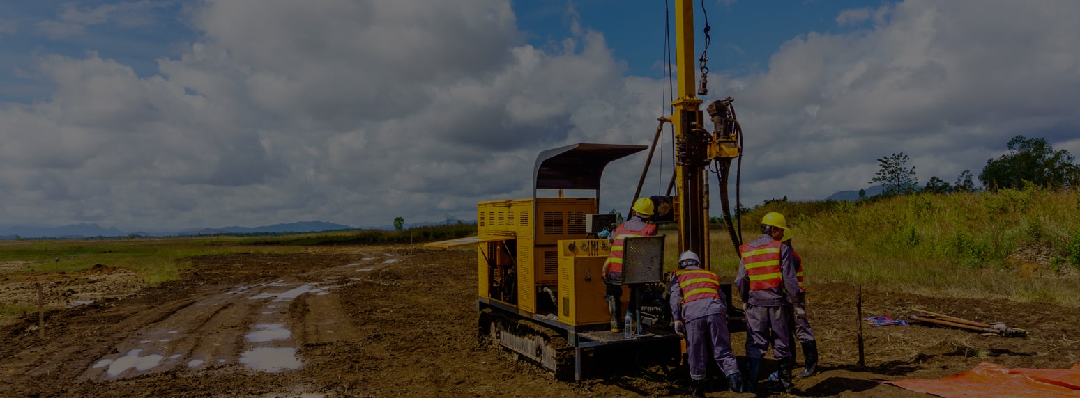 A rotary drilling rig and crew working on a prepared site